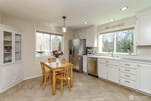 kitchen with stainless steel appliances, a sink, light countertops, and white cabinets