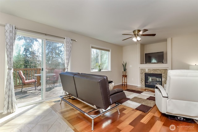 living room with a fireplace, baseboards, and a ceiling fan