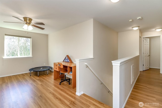 home office with baseboards, ceiling fan, and light wood finished floors