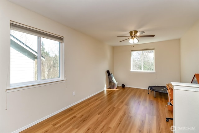 spare room with light wood finished floors, ceiling fan, and baseboards