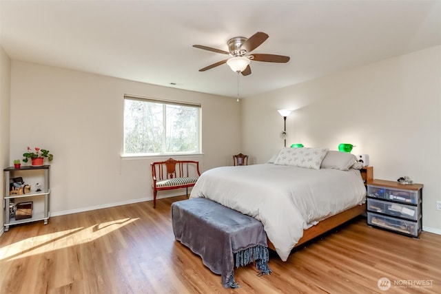 bedroom featuring a ceiling fan, visible vents, baseboards, and wood finished floors