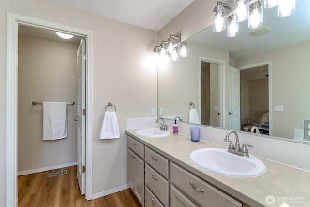 ensuite bathroom with double vanity, wood finished floors, a sink, and ensuite bathroom