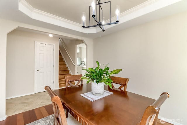 dining space featuring arched walkways, stairway, a tray ceiling, crown molding, and a notable chandelier