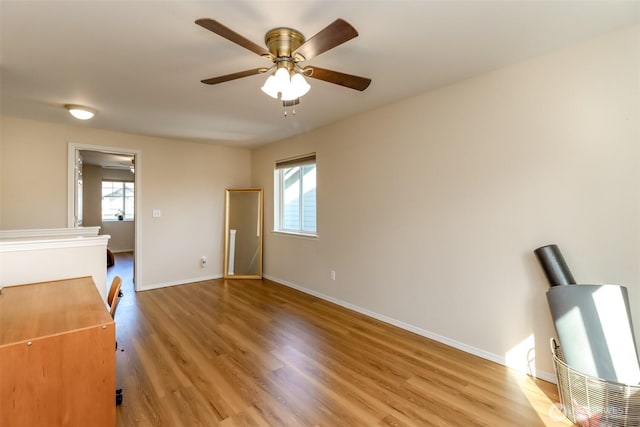 unfurnished bedroom featuring multiple windows, light wood-style flooring, and baseboards