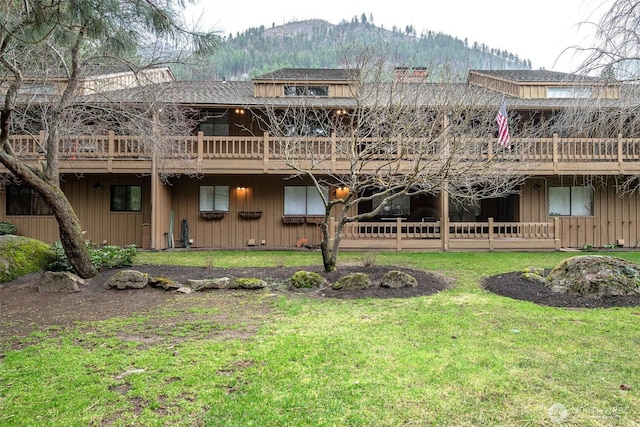 rear view of property with a deck with mountain view and a yard