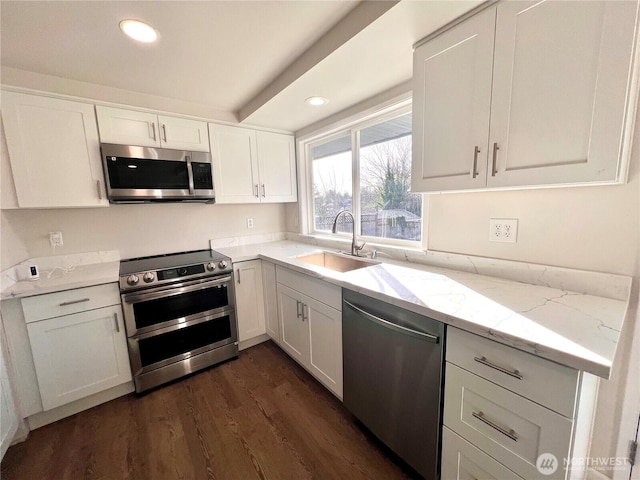 kitchen with dark wood-style floors, stainless steel appliances, a sink, and white cabinets