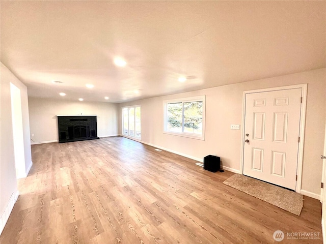 unfurnished living room featuring a fireplace, baseboards, and wood finished floors