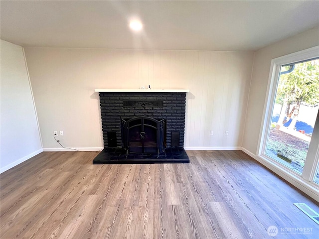 room details with a brick fireplace, visible vents, baseboards, and wood finished floors