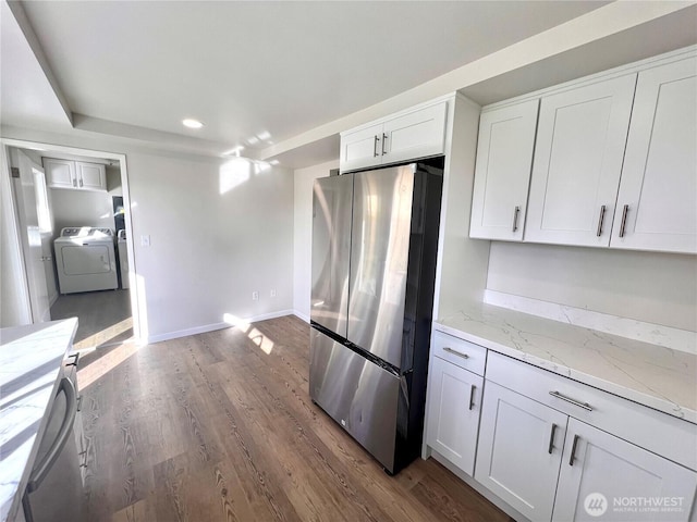 kitchen featuring washer / dryer, white cabinets, dark wood finished floors, light stone counters, and freestanding refrigerator