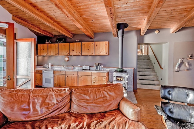 kitchen featuring wooden ceiling, a wood stove, a sink, light countertops, and beam ceiling