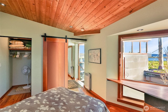 bedroom with a barn door, wood finished floors, wood ceiling, a closet, and radiator