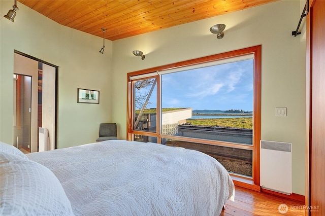 bedroom featuring wooden ceiling, a water view, light wood finished floors, and radiator heating unit