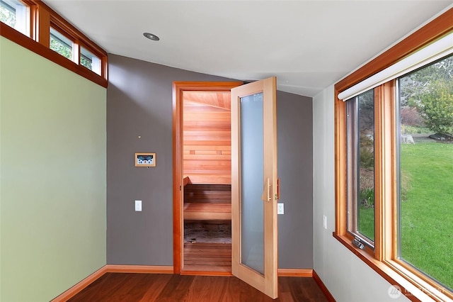 corridor featuring dark wood-type flooring and baseboards