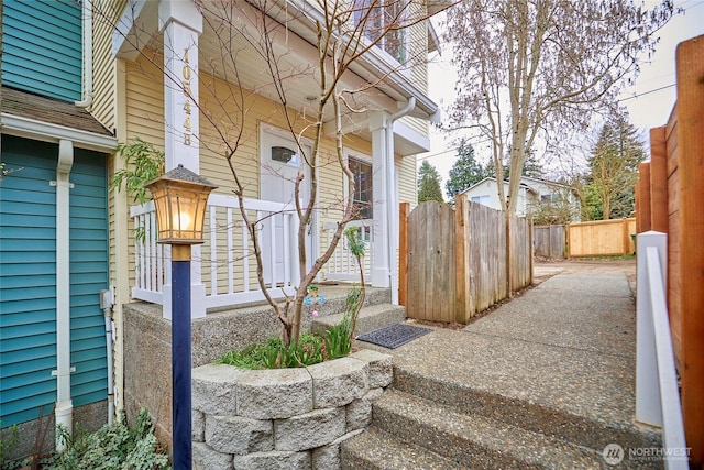 doorway to property with a porch and fence