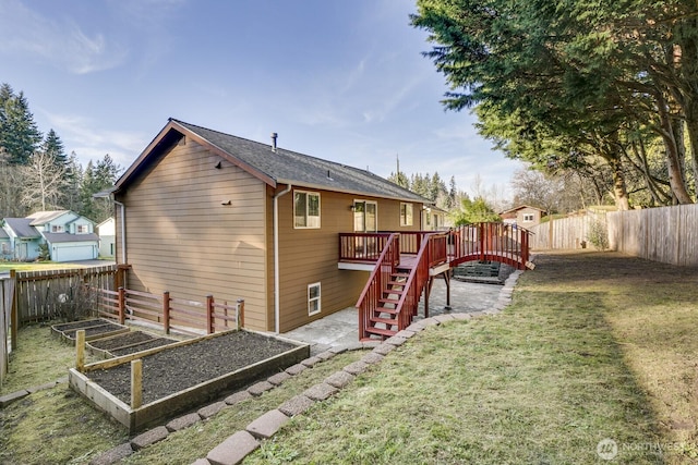 rear view of house with a fenced backyard, a garden, stairway, a lawn, and a wooden deck