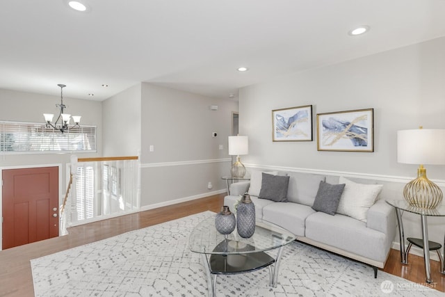 living area featuring a notable chandelier, baseboards, wood finished floors, and recessed lighting