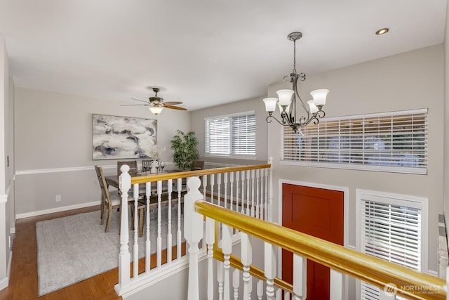 hall featuring baseboards, wood finished floors, an inviting chandelier, an upstairs landing, and recessed lighting