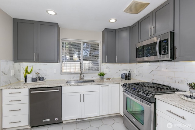 kitchen with light stone counters, appliances with stainless steel finishes, a sink, and visible vents