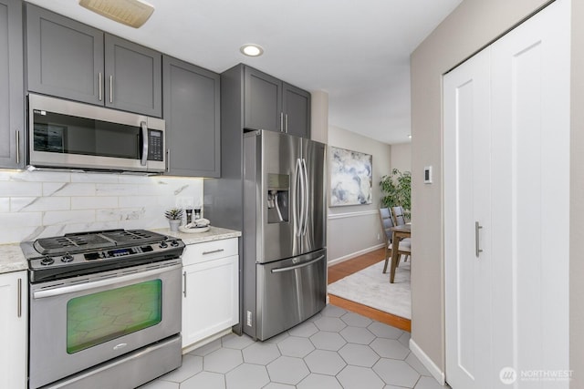 kitchen featuring light stone counters, recessed lighting, backsplash, appliances with stainless steel finishes, and baseboards