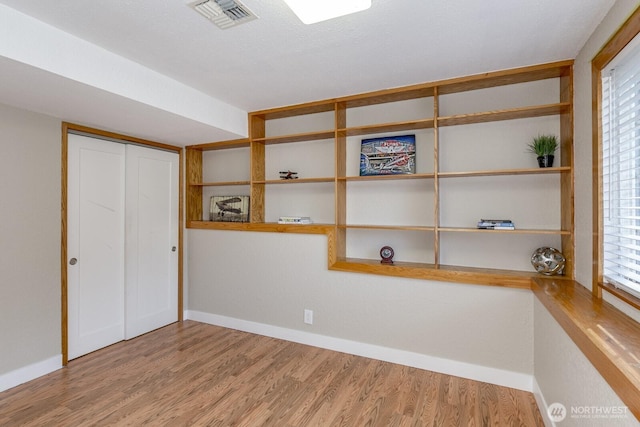 unfurnished room with wood finished floors, visible vents, and baseboards