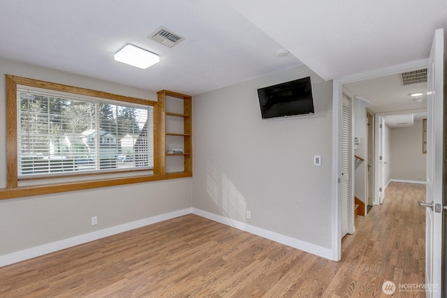 unfurnished room with light wood finished floors, baseboards, and visible vents