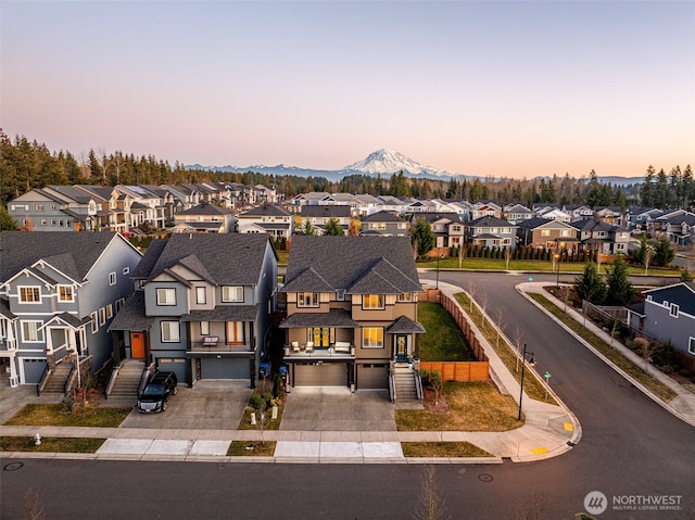 exterior space with an attached garage, a mountain view, fence, concrete driveway, and a residential view