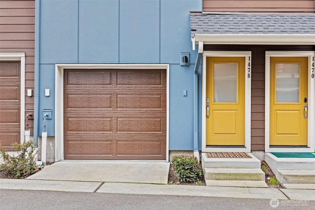 entrance to property with a garage, roof with shingles, and driveway