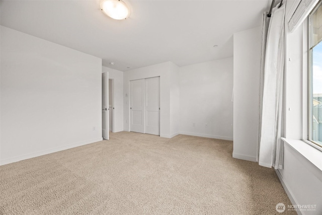 spare room featuring light carpet, a healthy amount of sunlight, and baseboards