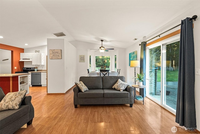 living area with light wood finished floors, visible vents, and vaulted ceiling