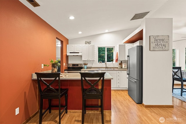 kitchen with under cabinet range hood, a peninsula, a sink, visible vents, and appliances with stainless steel finishes