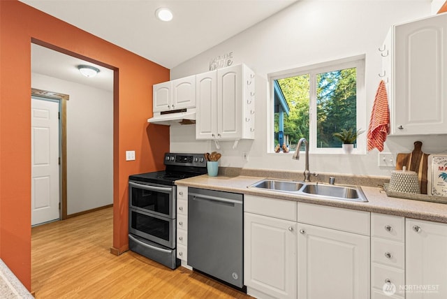 kitchen featuring appliances with stainless steel finishes, white cabinets, a sink, light wood-type flooring, and under cabinet range hood