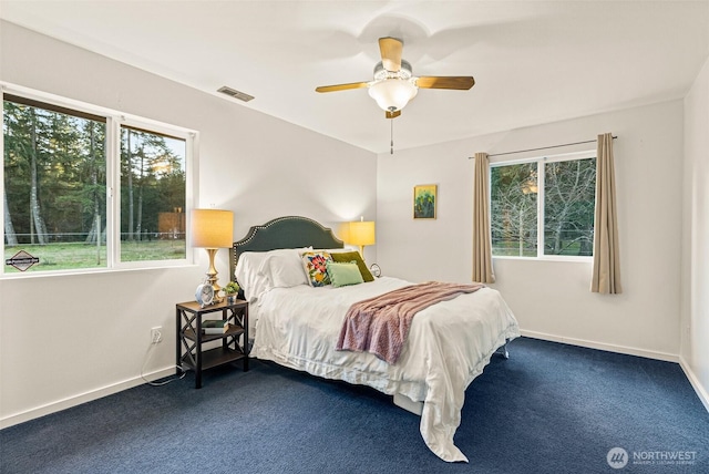 carpeted bedroom with baseboards, multiple windows, visible vents, and ceiling fan