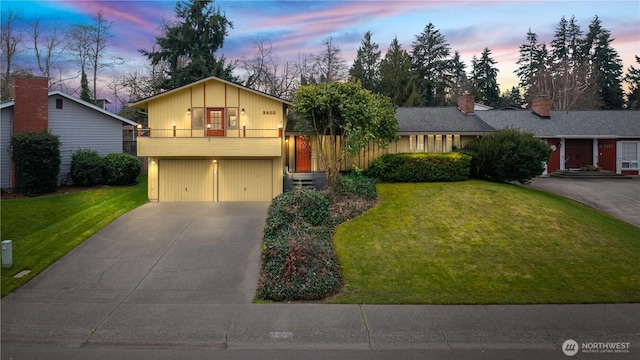 view of front of home featuring a garage, concrete driveway, a yard, and a balcony