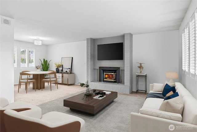 living room featuring carpet floors, a brick fireplace, and visible vents