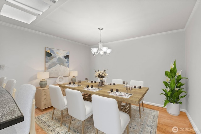 dining room with a chandelier, light wood finished floors, crown molding, and baseboards