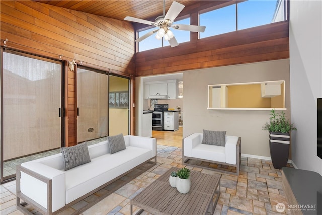 living area with wood ceiling, stone finish flooring, ceiling fan, high vaulted ceiling, and baseboards