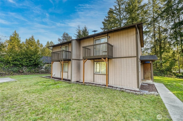 rear view of property featuring a yard and a balcony