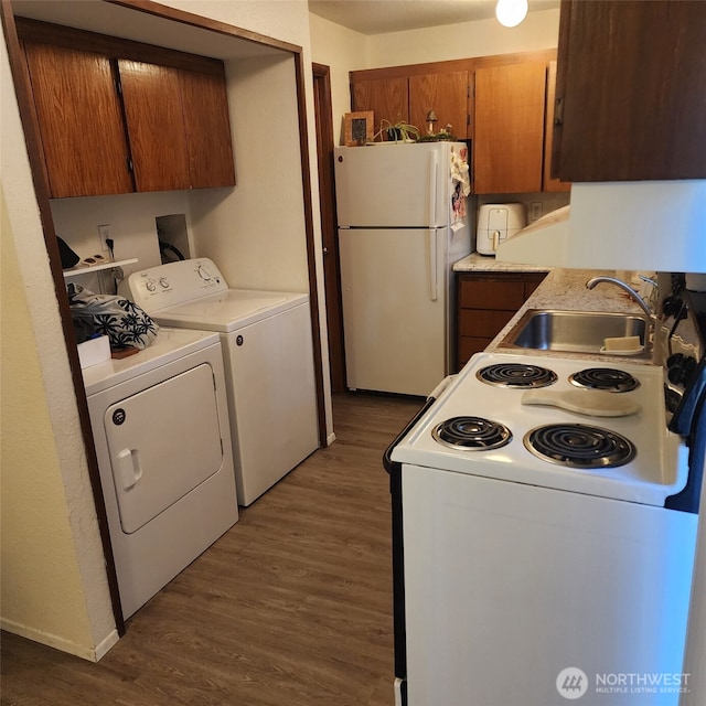 kitchen featuring dark wood-style floors, washing machine and clothes dryer, light countertops, a sink, and white appliances