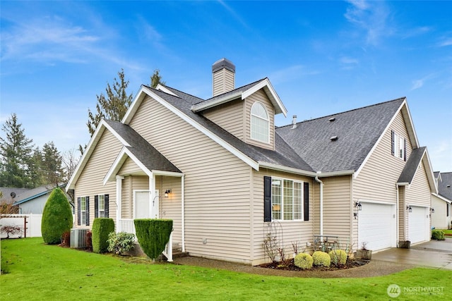 view of front of home featuring a garage, concrete driveway, a front yard, and roof with shingles