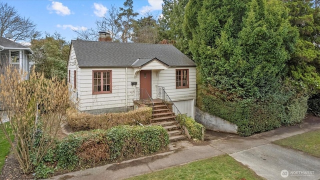 bungalow with concrete driveway, roof with shingles, and a chimney