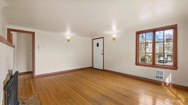 unfurnished living room with visible vents, radiator heating unit, baseboards, and wood finished floors