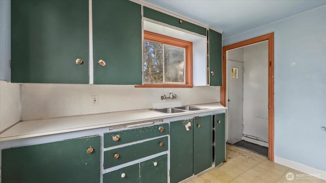 kitchen featuring green cabinetry, light countertops, and a sink