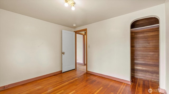 spare room with baseboards and wood-type flooring