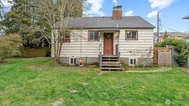 rear view of property with a yard, roof with shingles, a chimney, and fence