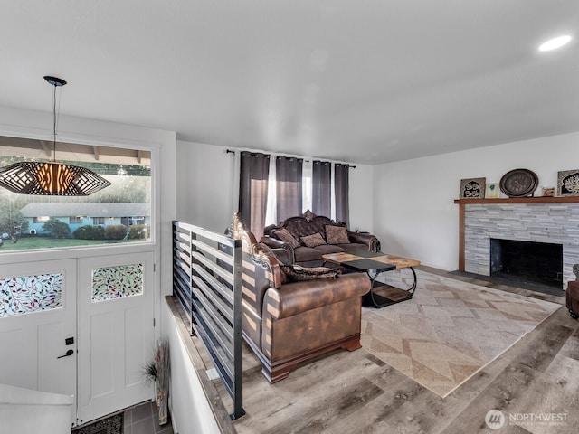 living area with a stone fireplace and wood finished floors