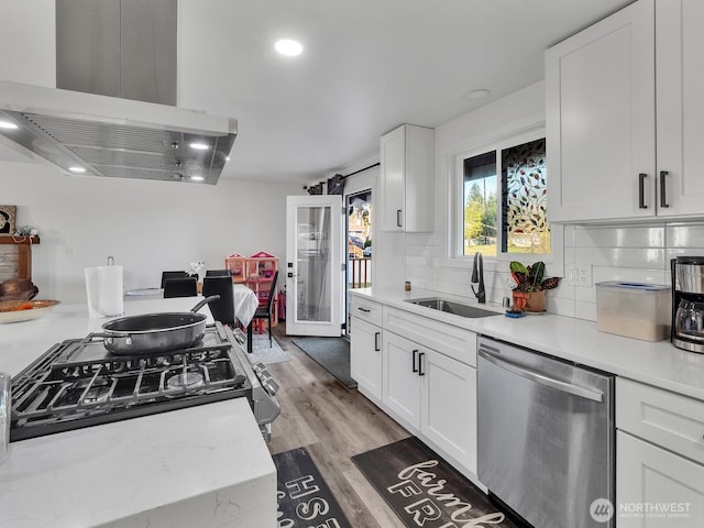 kitchen featuring light wood-style floors, white cabinetry, a sink, island range hood, and dishwasher