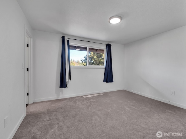 spare room with carpet, visible vents, and baseboards