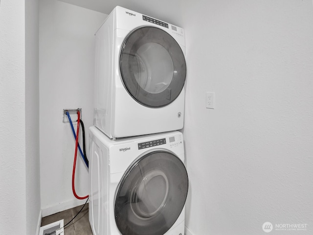 laundry room with baseboards, laundry area, and stacked washer / drying machine