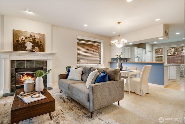 living room featuring light carpet, a notable chandelier, recessed lighting, a fireplace, and baseboards