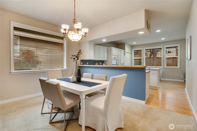 dining space with recessed lighting, baseboards, an inviting chandelier, and light carpet